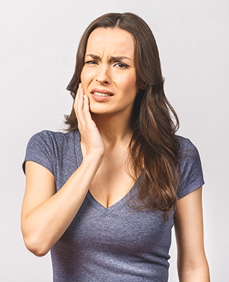 Grimacing woman touching the side of her face